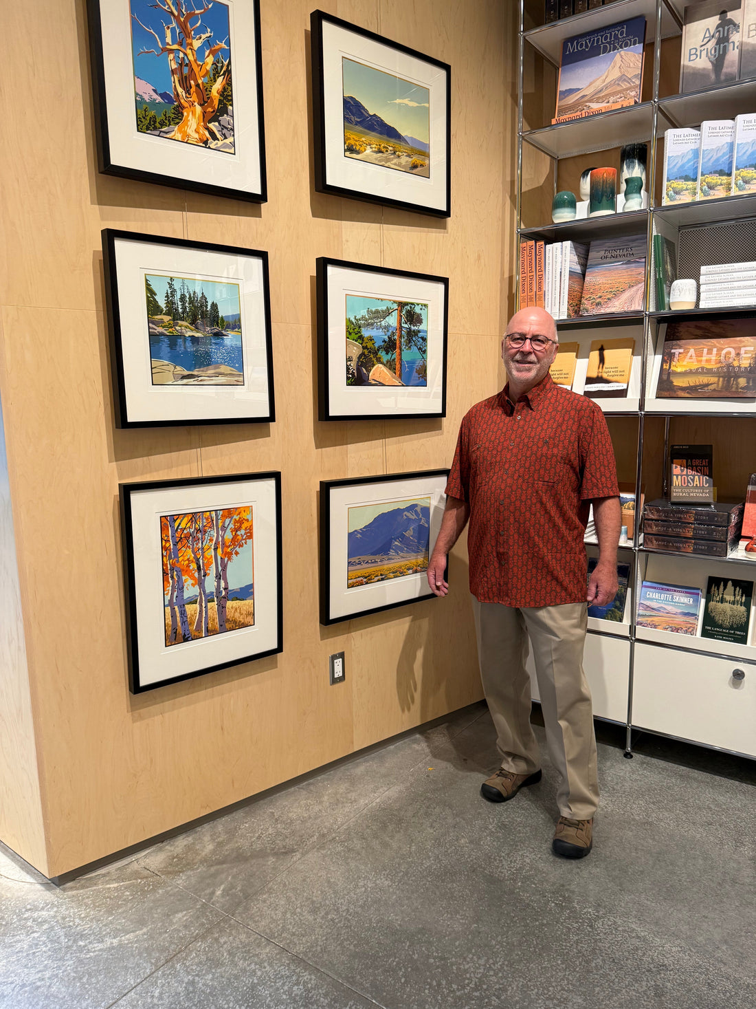 Craig Mitchell standing beside six framed Nevada and Lake Tahoe landscape block prints displayed at the Bretzlaff Book Shop, Nevada Museum of Art