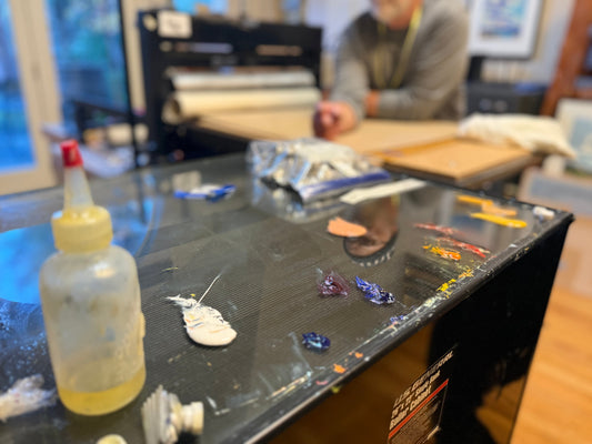 Paint samples in front of a block print machine with an artist visible in the background