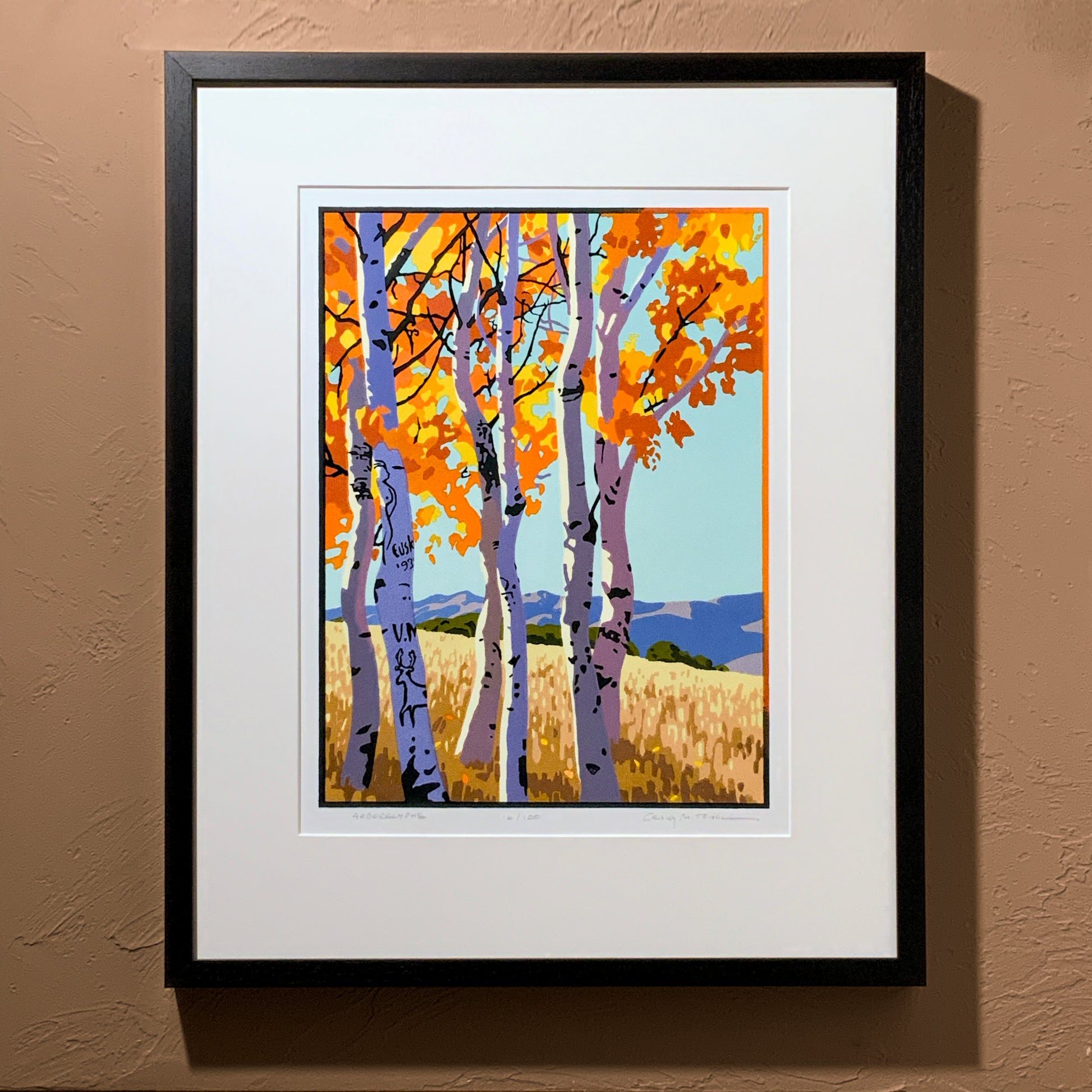 A framed art print depicting a grove of aspen trees with autumn-colored leaves and arboglyphs, displayed on a wall.