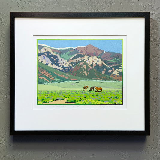Wild horse artwork with mountain backdrop framed against a neutral wall