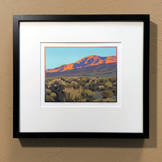 A framed art print titled 'Desert Finale' depicting a mountain landscape with a pink and orange sunset, set in a black frame.